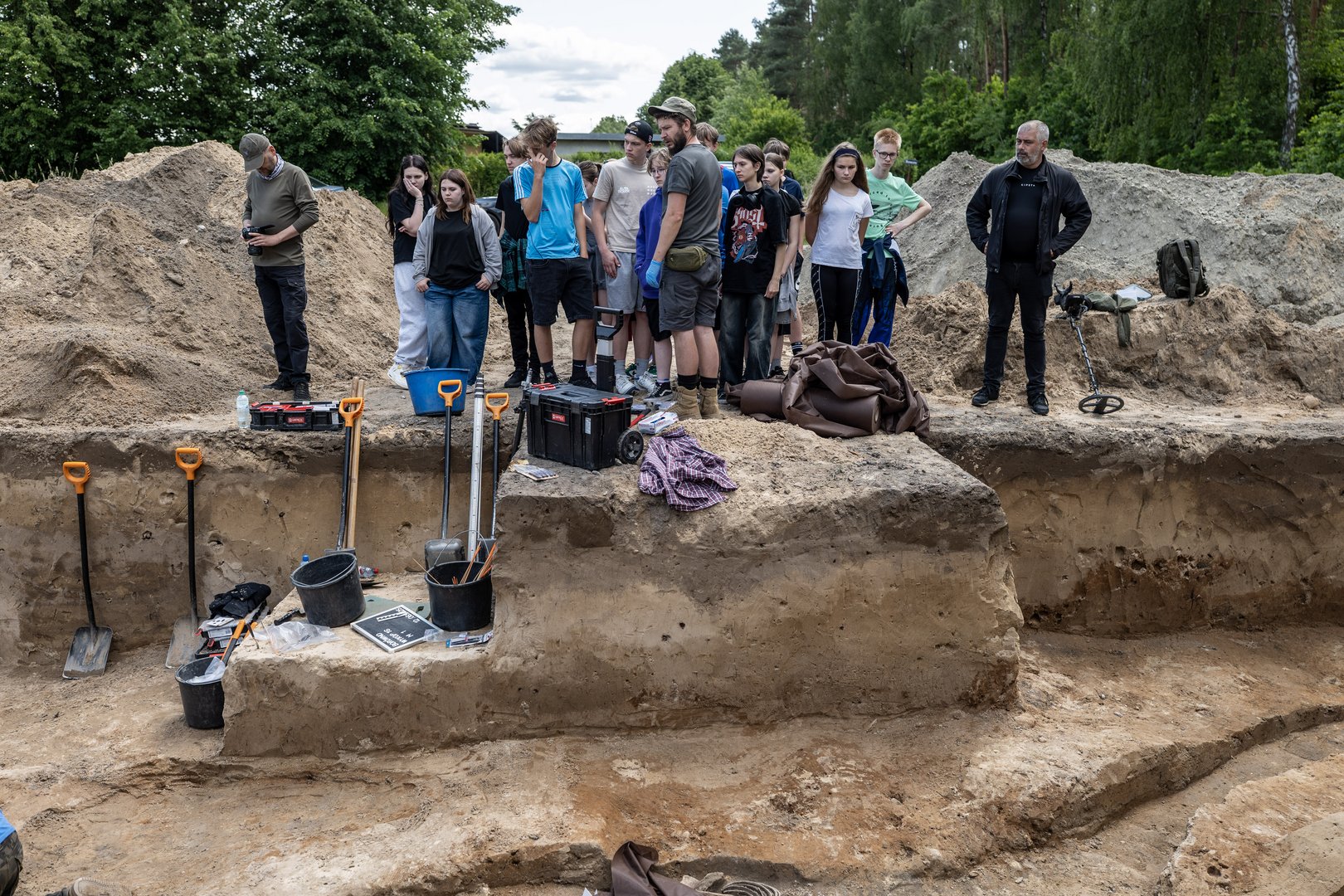 Dr Dawid Kobiałka prezentujący jeden z wykopów przybyłej na miejsce młodzieży